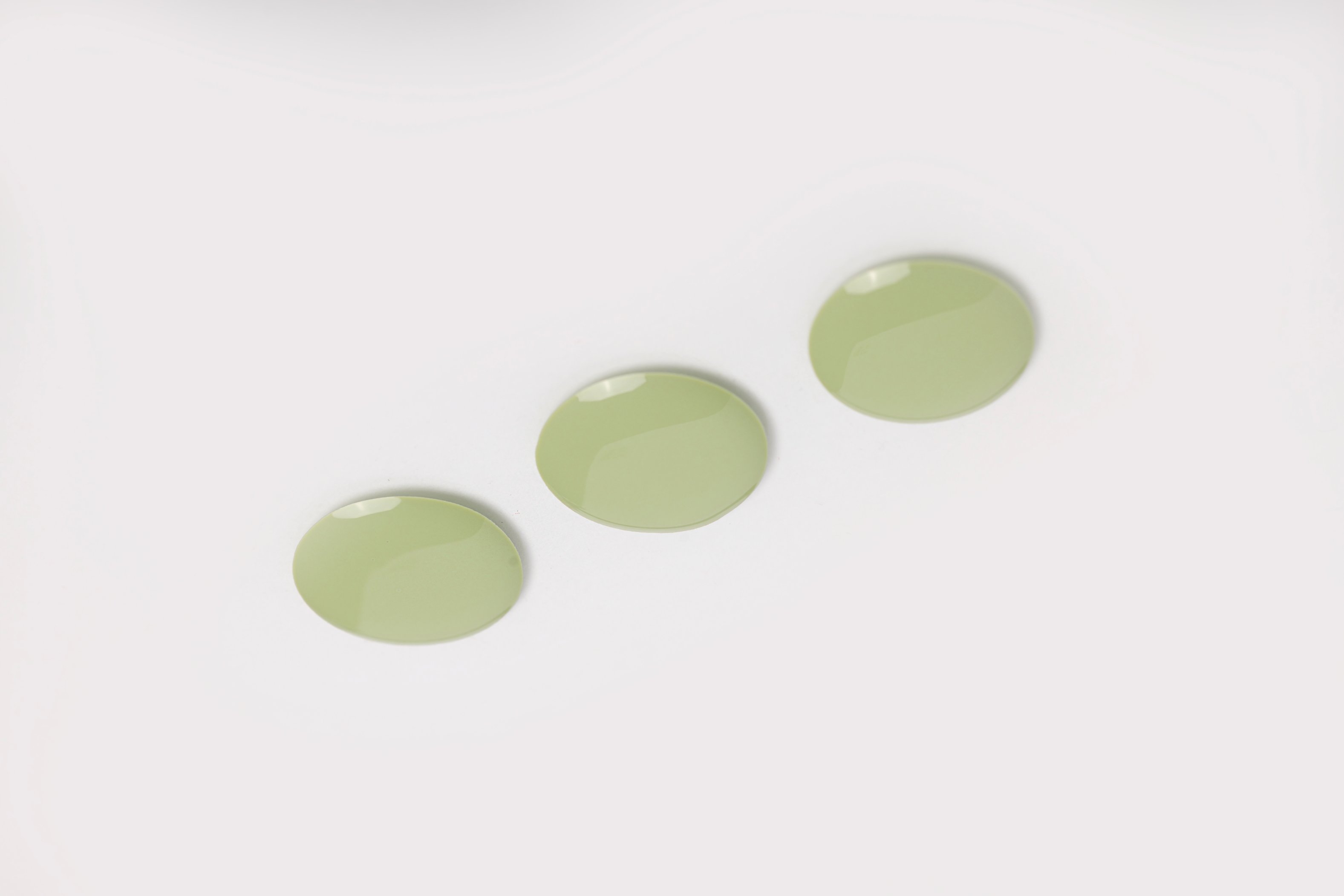 Drops of green makeup on a grey surface