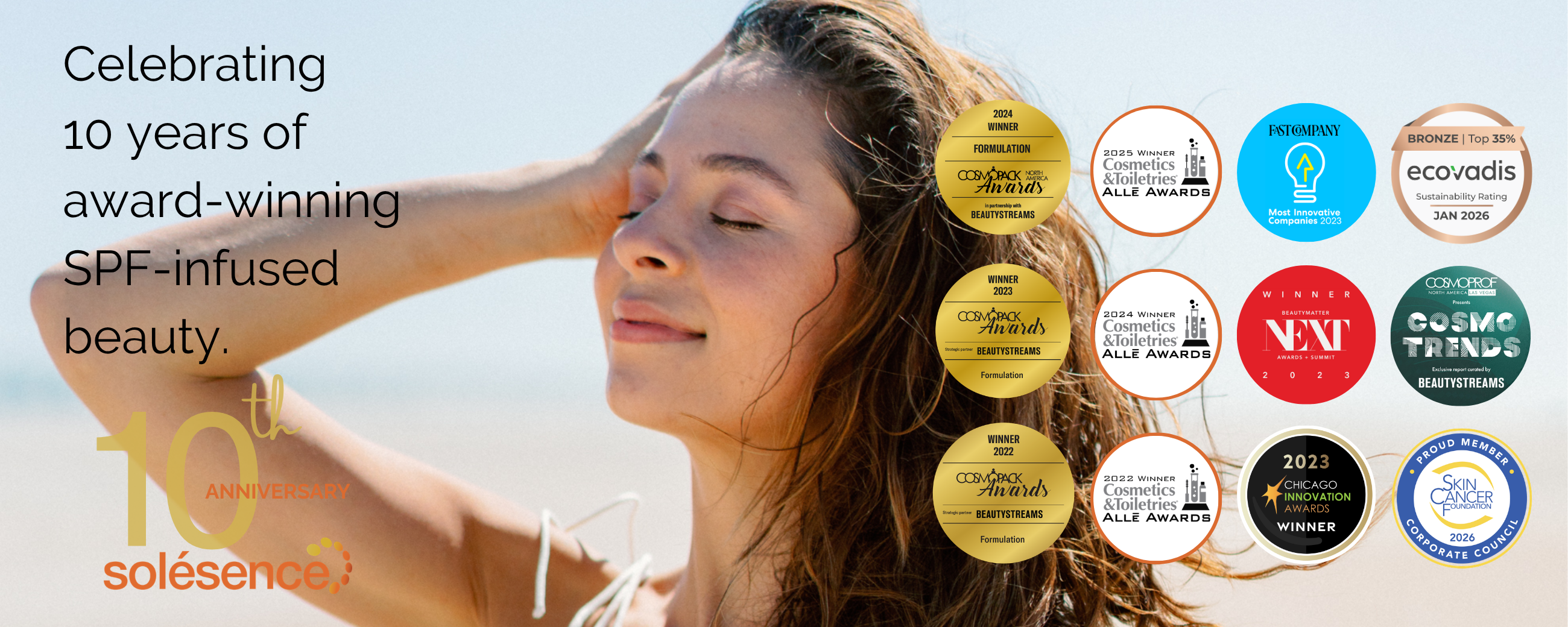 A woman standing on a beach and running her hands over her hair.