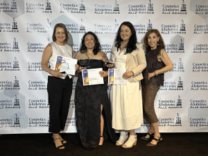 Four women standing in a row and holding award certificates.