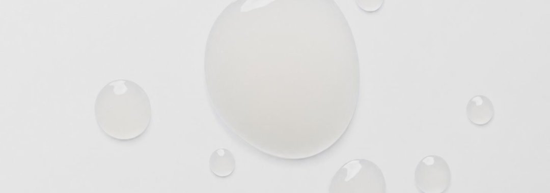 Dots of translucent serum on a white background.